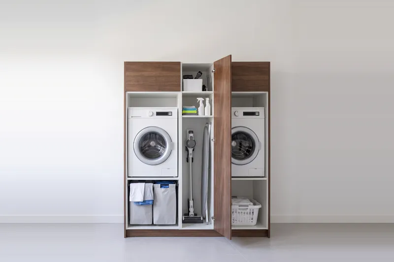 Impressie: twee wasmachinekasten met een kast, 173,8 cm breed en 210 cm hoog, fronten in walnoot, met deuren open.