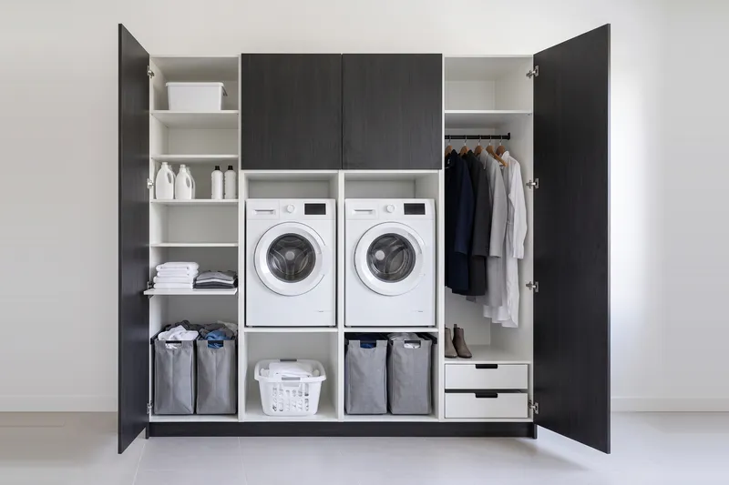 Impressie: twee wasmachinekasten met twee kasten, 253,9 cm breed en 250 cm hoog, fronten in zwart eiken, met deuren open.