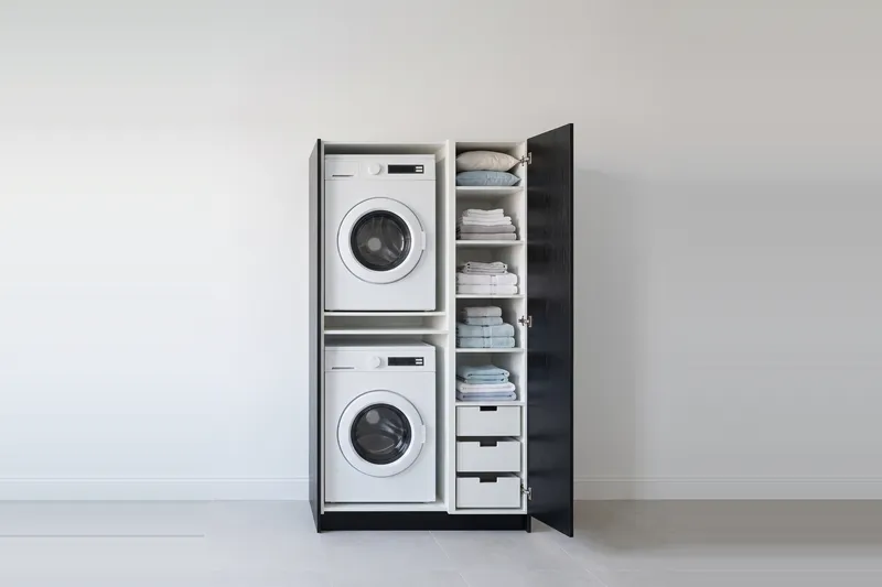 Impressie: wasmachinekast met een kast, 113,7 cm breed en 210 cm hoog, fronten in zwart eiken, met deuren open.