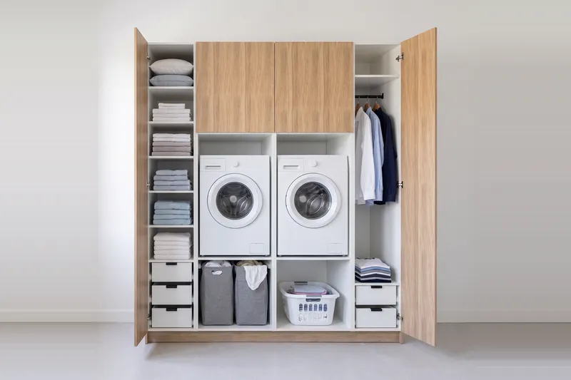 Impressie: twee wasmachinekasten met twee kasten, 213,9 cm breed en 250 cm hoog, fronten in naturel eiken, met deuren open.
