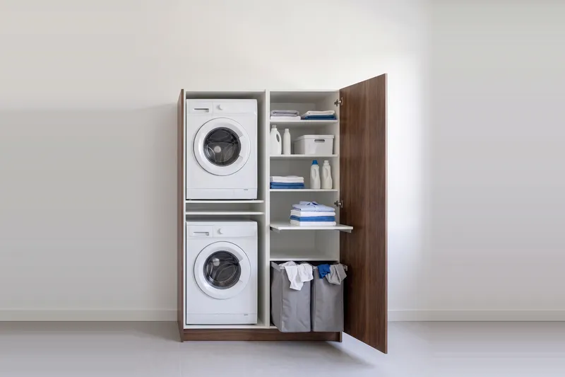 Impressie: wasmachinekast met een kast, 133,7 cm breed en 210 cm hoog, fronten in walnoot, met deuren open.