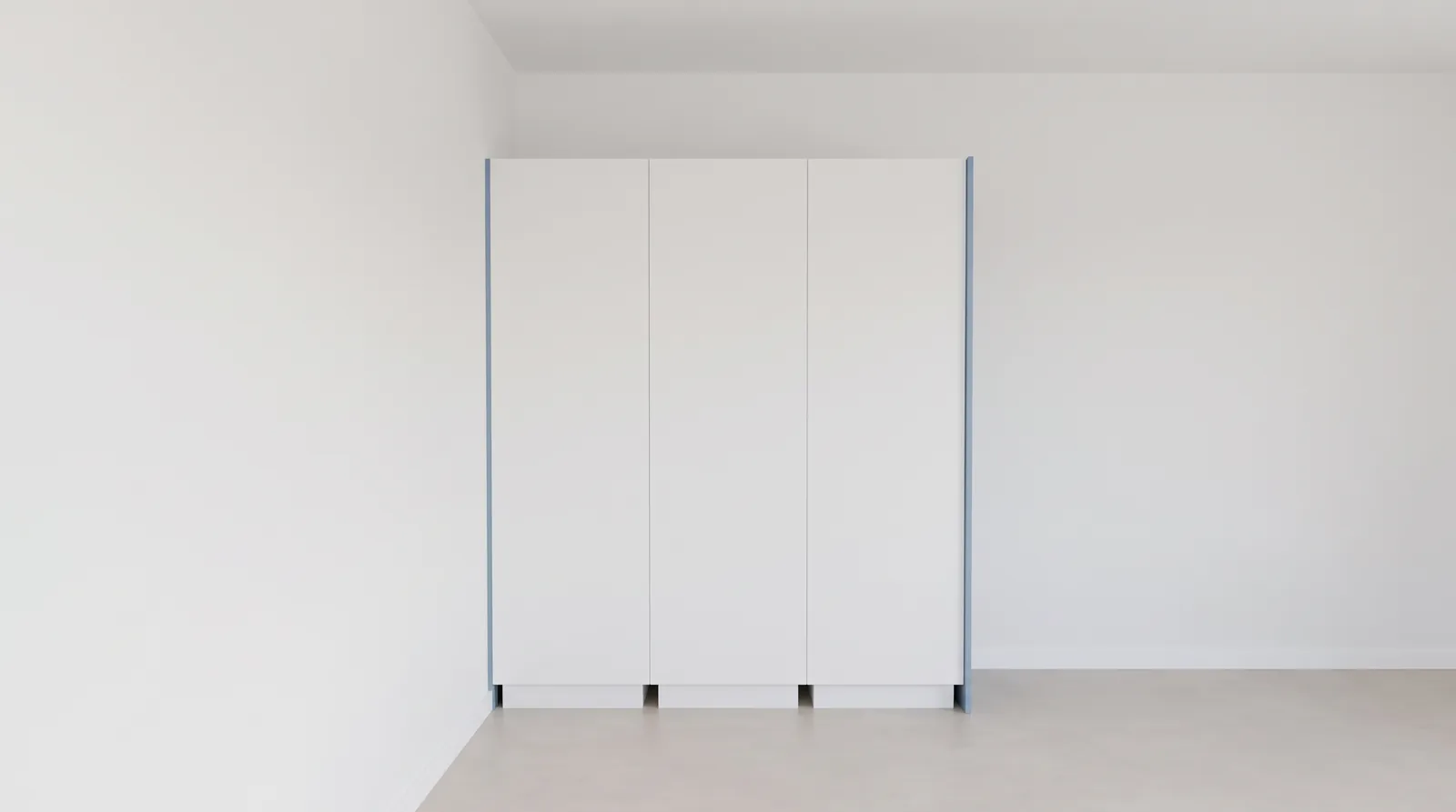 Tegen een zijmuur: drie witte kasten, de afwerking aan de zijkanten in blauw.